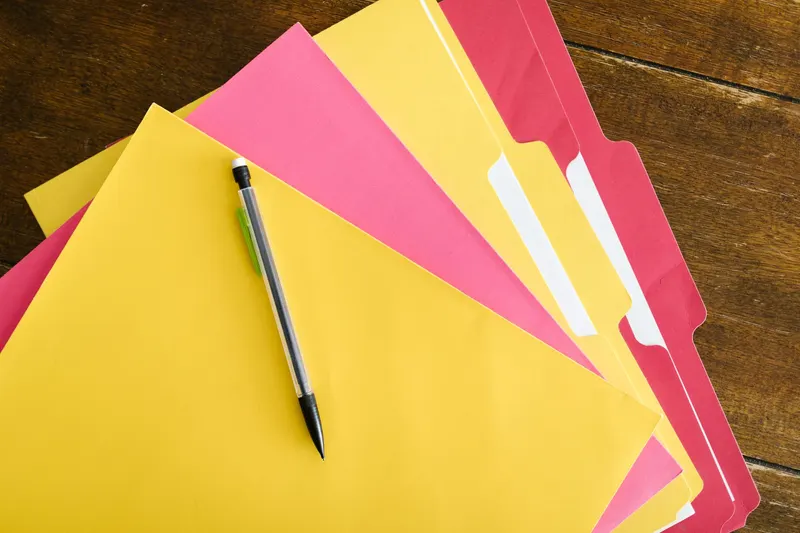 A stack of organised folders with colored index tabs on a wooden table