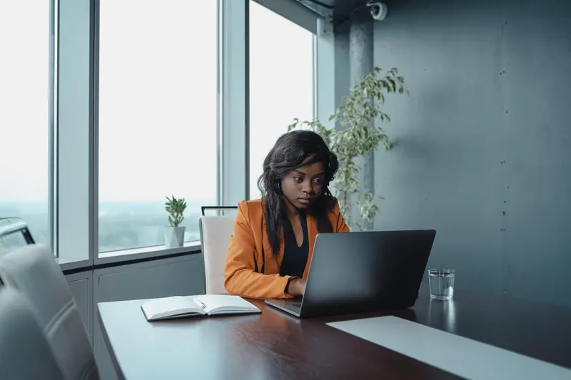 An HR manager working on a laptop at a desk in a modern office