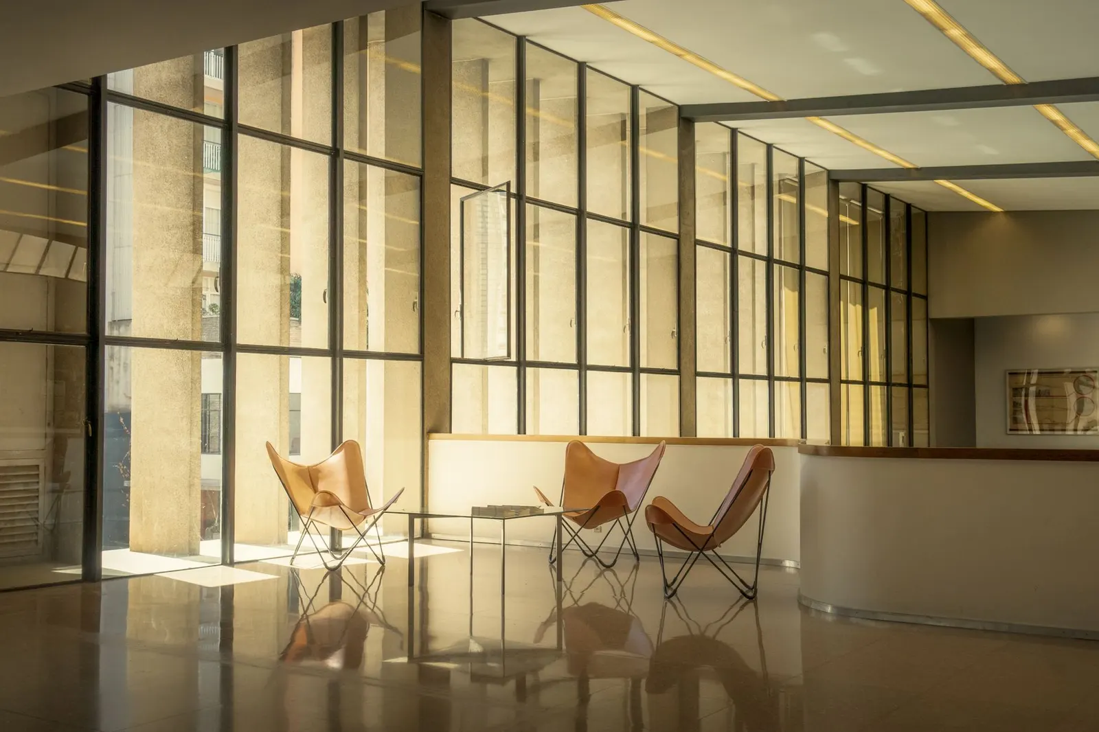 A modern office lounge with leather chairs, glass walls and warm natural light